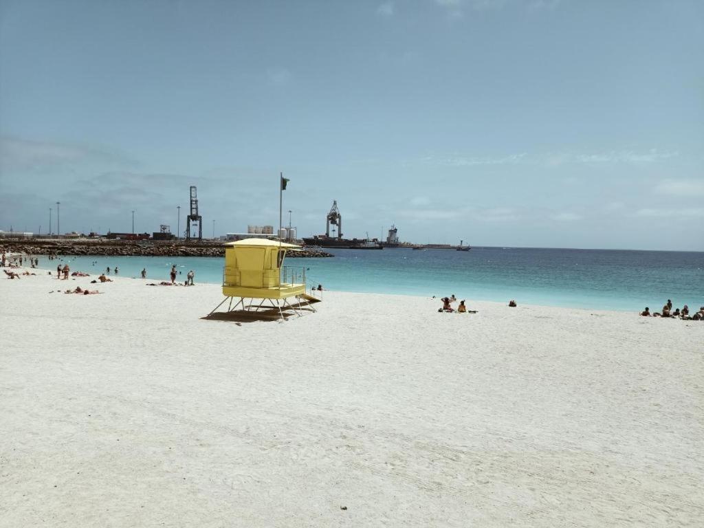 een groep mensen op een strand bij het water bij ALOJAMIENTO PLAYA CHICA, LOS POZOS HABITACIONES in Puerto del Rosario