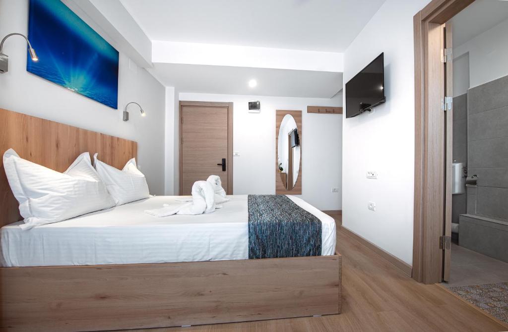 a bedroom with a bed with white sheets and a television at Polu-X in Vama Veche