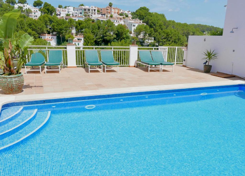 a swimming pool with blue chairs next to a building at Es Cucó in Cala Galdana