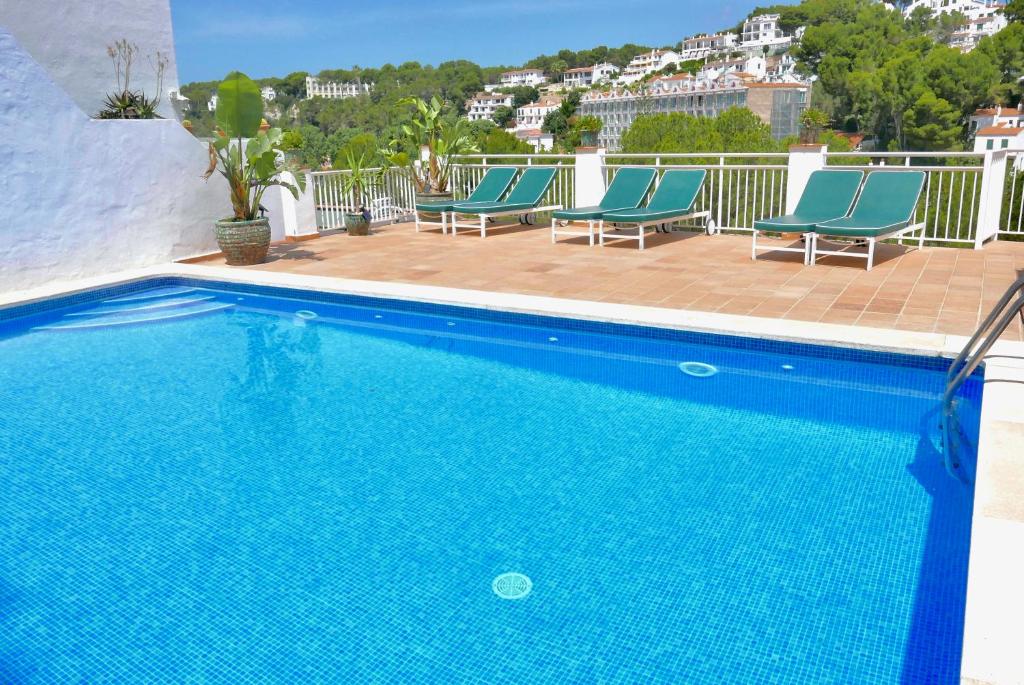 a blue swimming pool with blue chairs on a balcony at Es Cucó in Cala Galdana