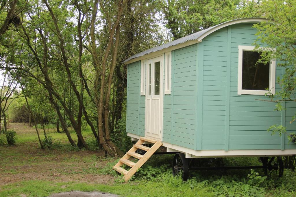 een blauw tiny house op een trailer in het bos bij The Tawny Shepherd Hut, Whitehouse Farm in Stowmarket