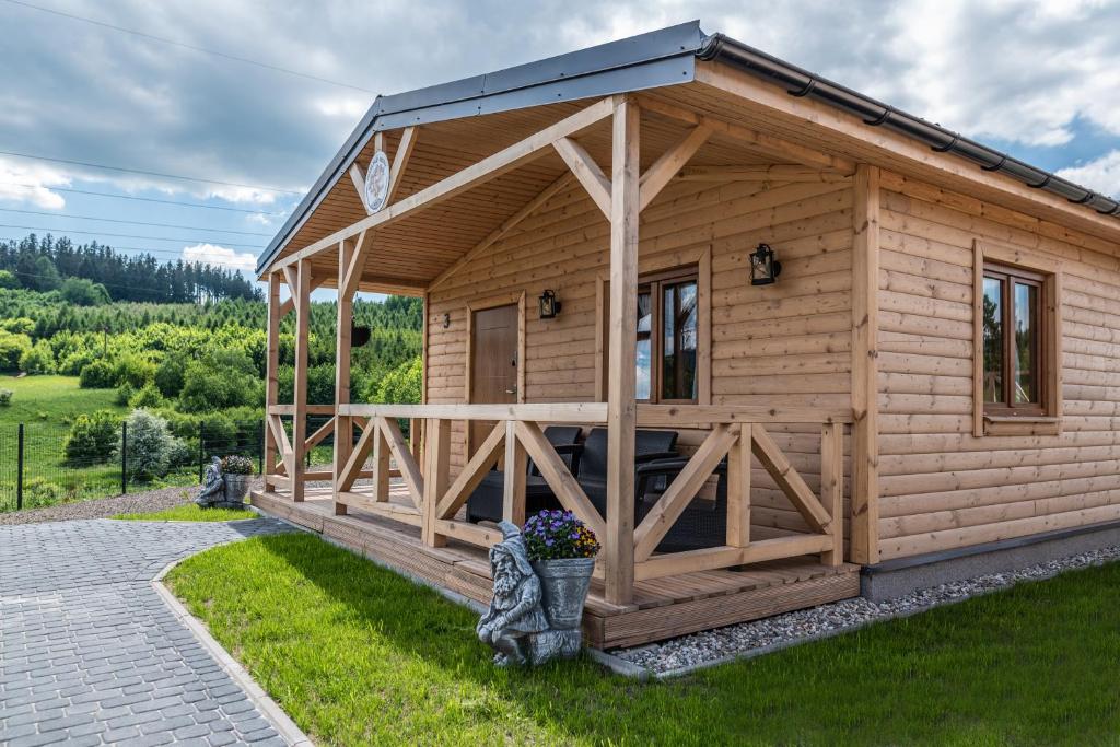 una cabina in legno con un portico nell'erba di Osada Trzy Siostry a Duszniki Zdrój