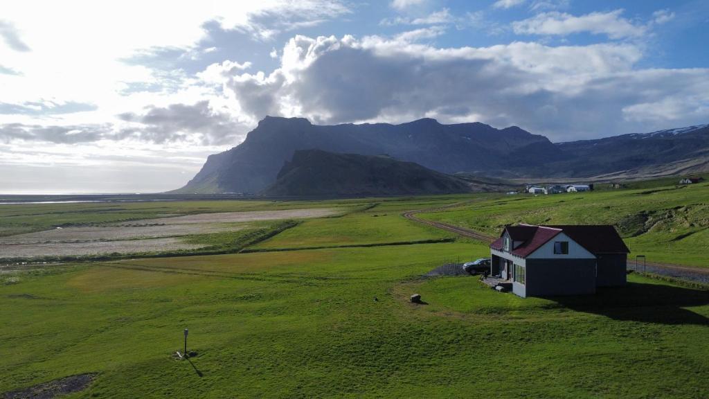 ein Haus auf einem Feld mit einem Berg im Hintergrund in der Unterkunft Guesthouse Rauðafell in Holt