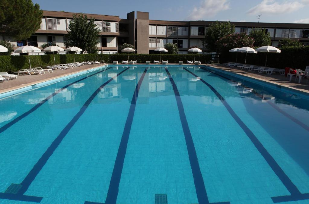 una gran piscina con sillas y sombrillas en Residence Habitat, en Marina di Bibbona