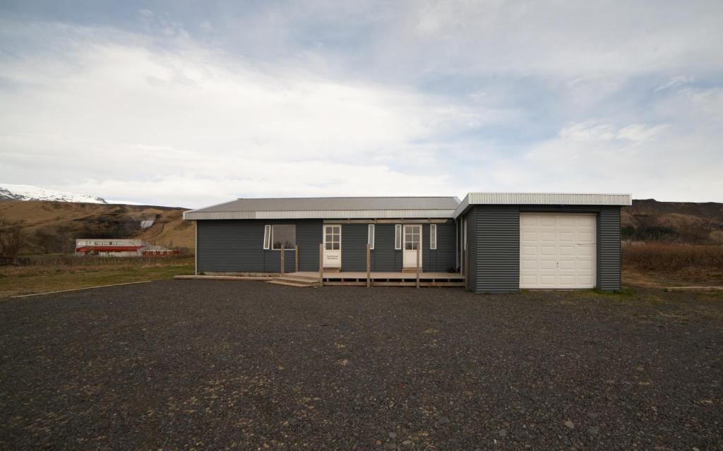 a house with a garage on a gravel lot at Guesthouse Skógafoss in Skogar