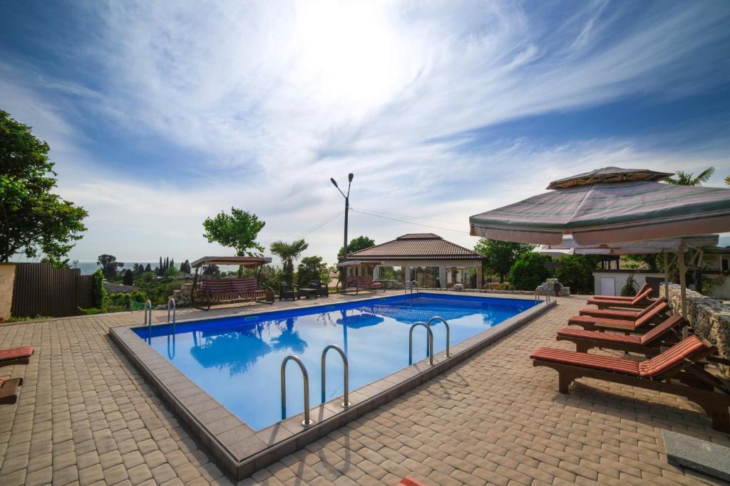 una grande piscina con sedie e gazebo di Hotel Paradise a Sukhum