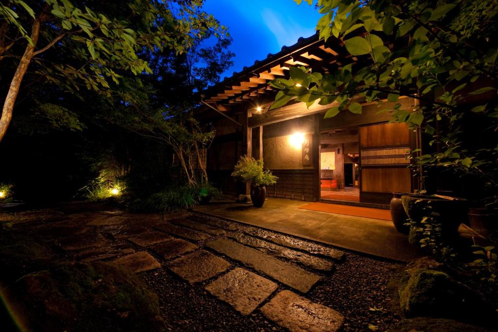 una casa con una pasarela de piedra delante por la noche en Yufuin Gettouan, en Yufu