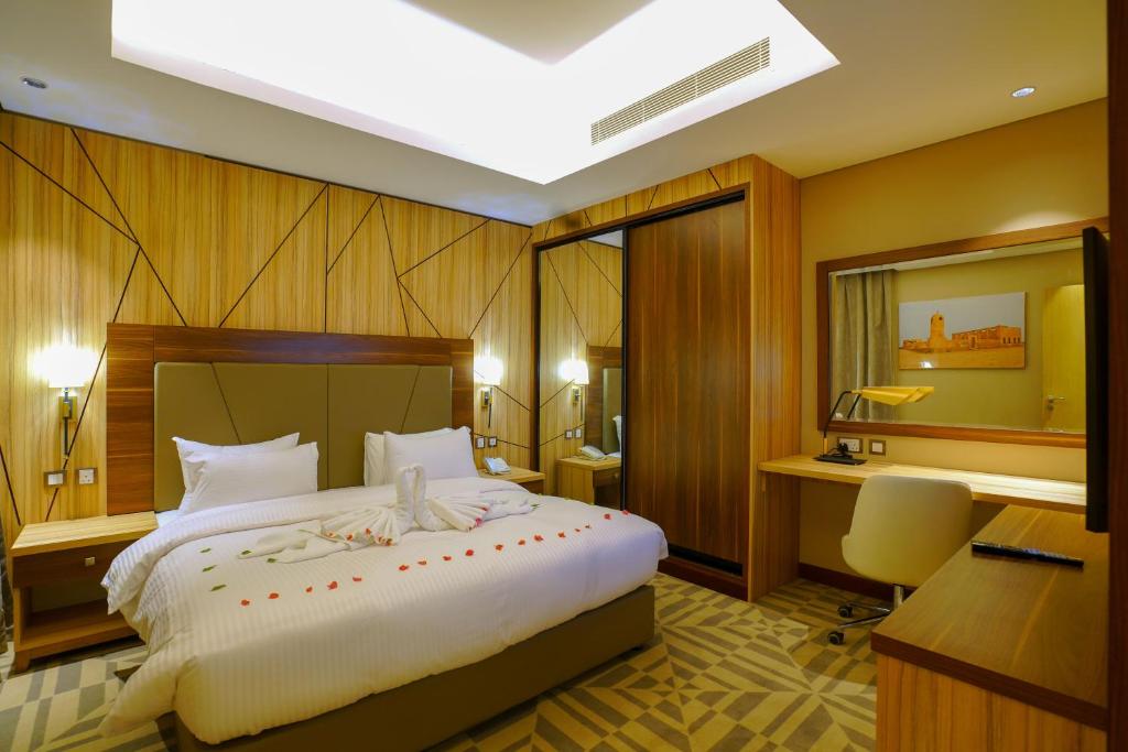 a bedroom with a large bed and a desk at Al Aseel Hotel in Doha
