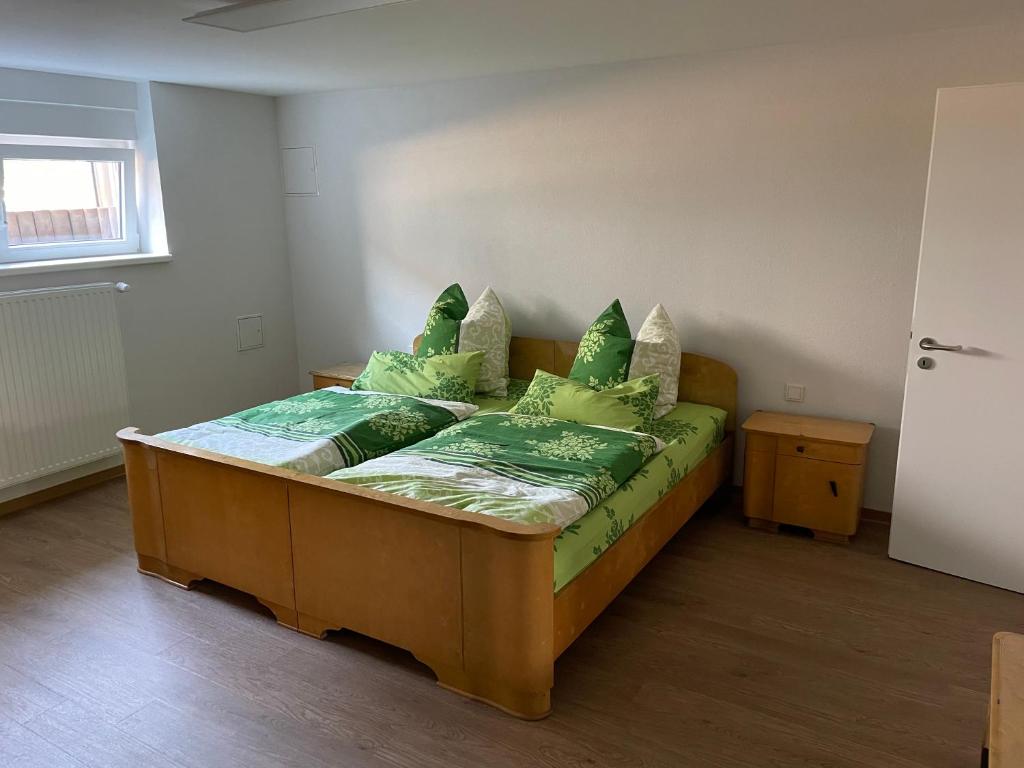 a bedroom with a wooden bed with green pillows at Ferienwohnung im Grünen in Lebach