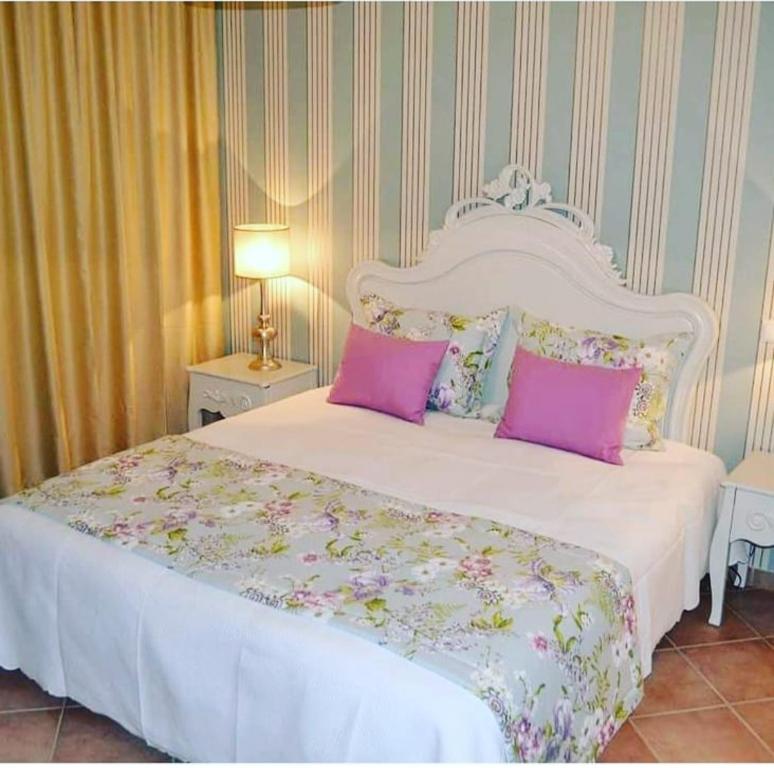 a bedroom with a white bed with pink pillows at Herdade Monte Gordo in Ourique