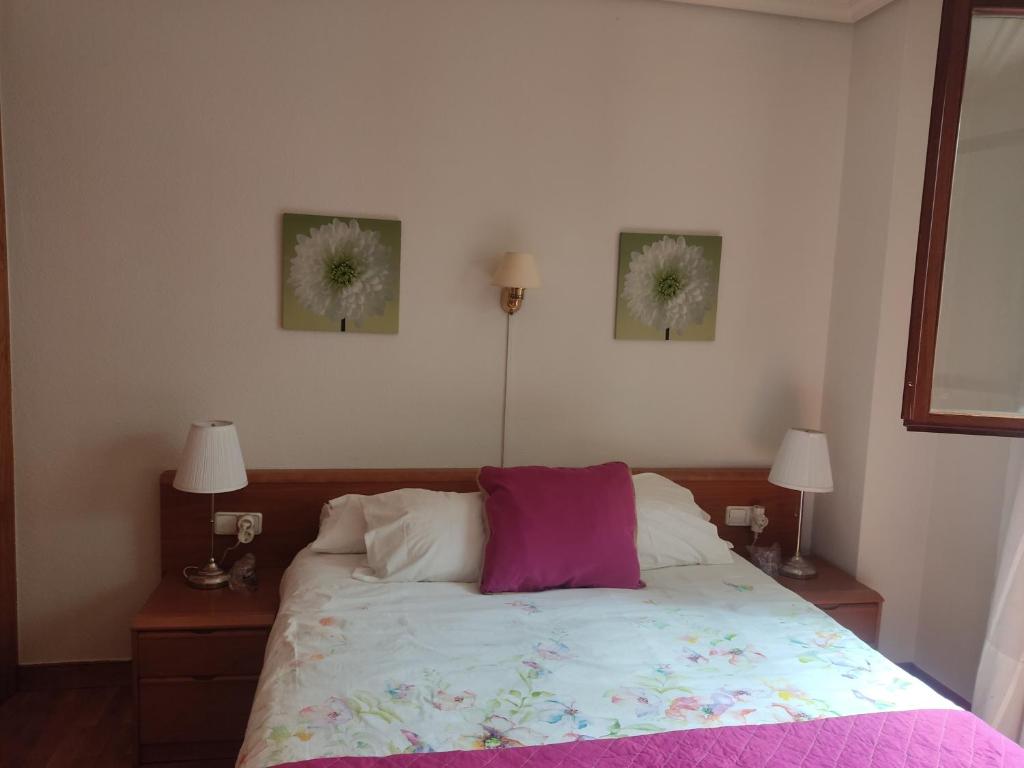 a bedroom with a bed with two pictures on the wall at Pension Payvi in Pamplona