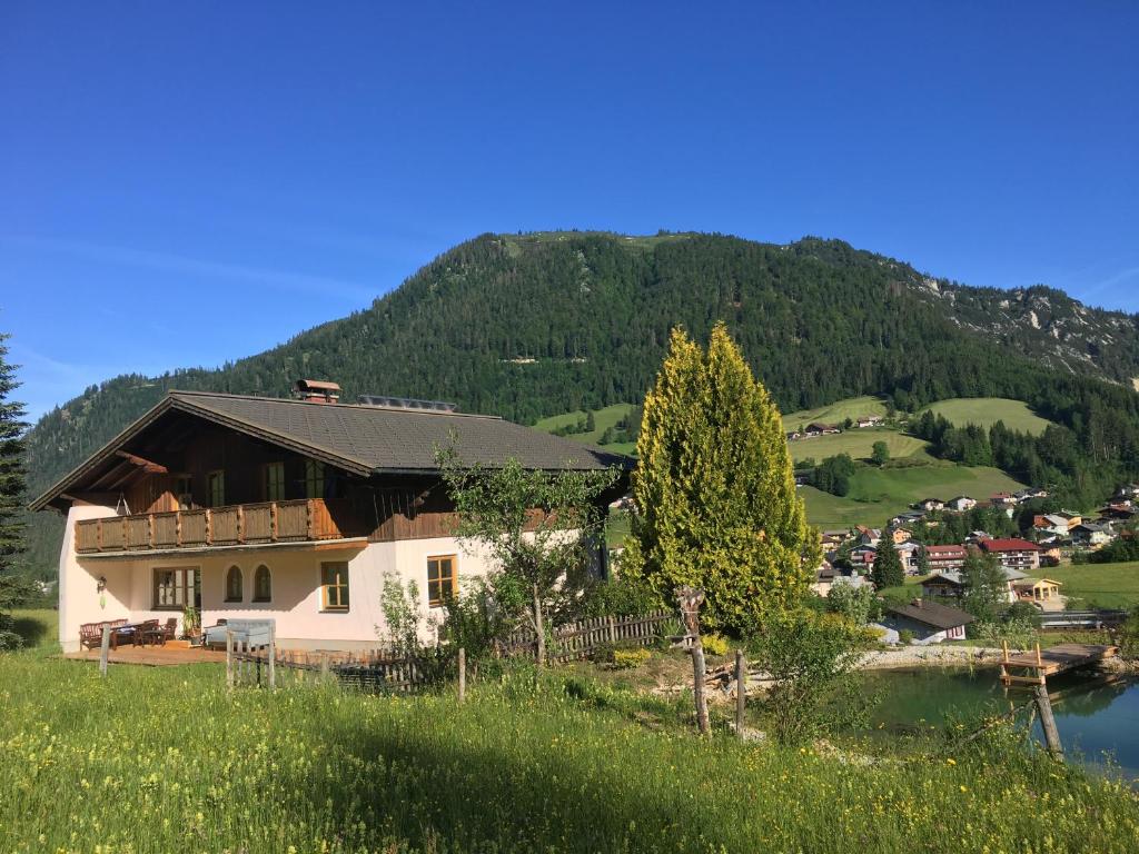a house on a hill next to a body of water at Schneckenhaus Dachstein West in Russbach am Pass Gschütt
