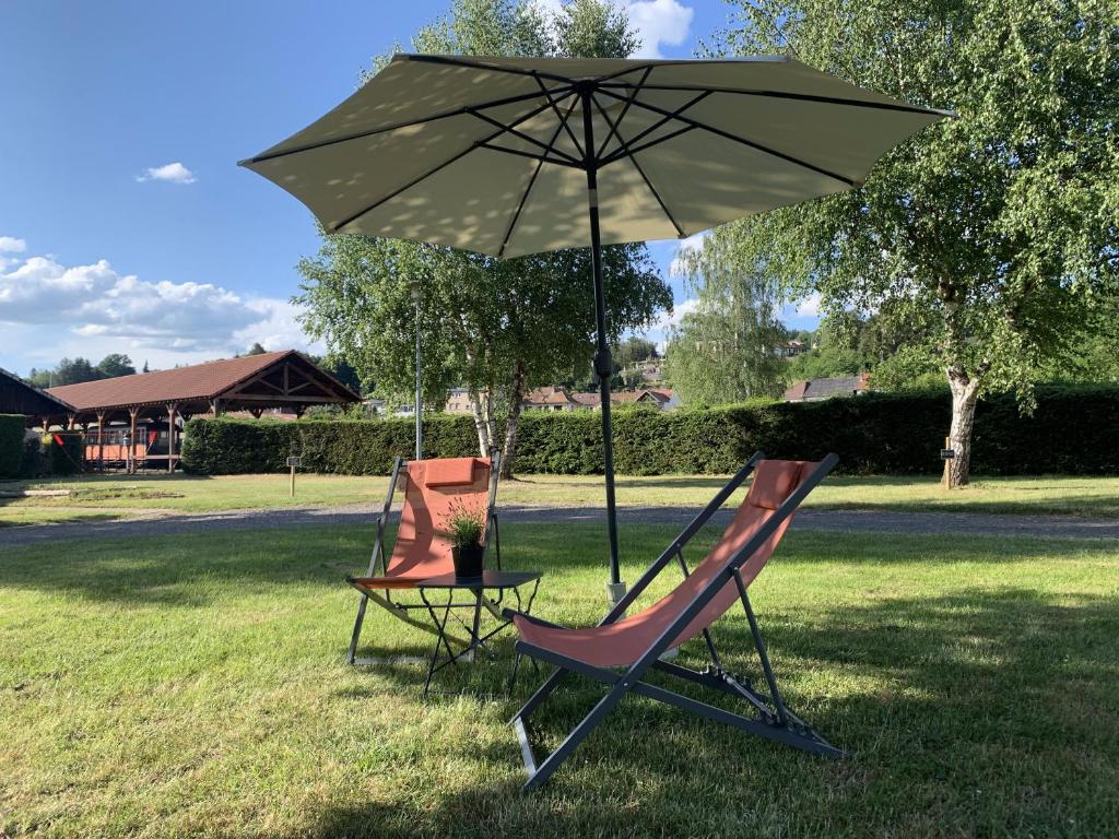 twee stoelen en een tafel met een paraplu bij Camping De La Sarre in Abreschviller