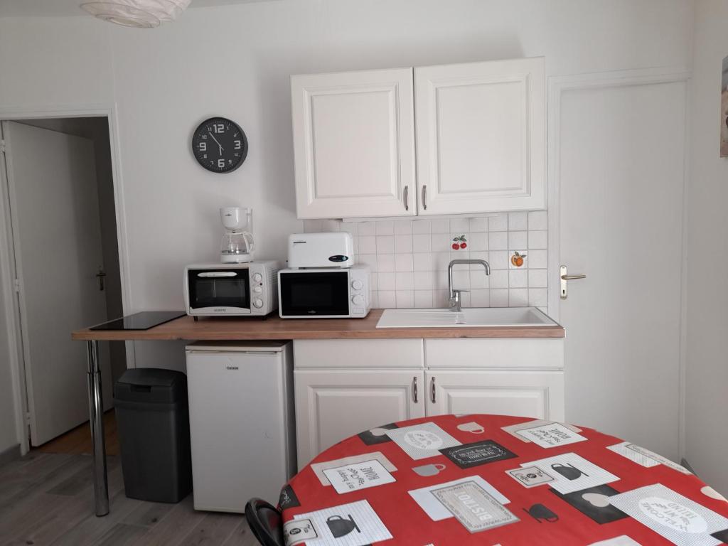 - une cuisine avec des placards blancs et un comptoir avec un évier dans l'établissement Promo F2 wifi Courseulles sur mer, à Courseulles-sur-Mer
