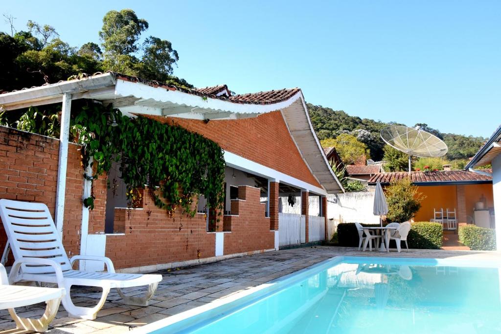 una casa con piscina y sillas junto a un edificio en Caminito, en Santo Antônio do Pinhal
