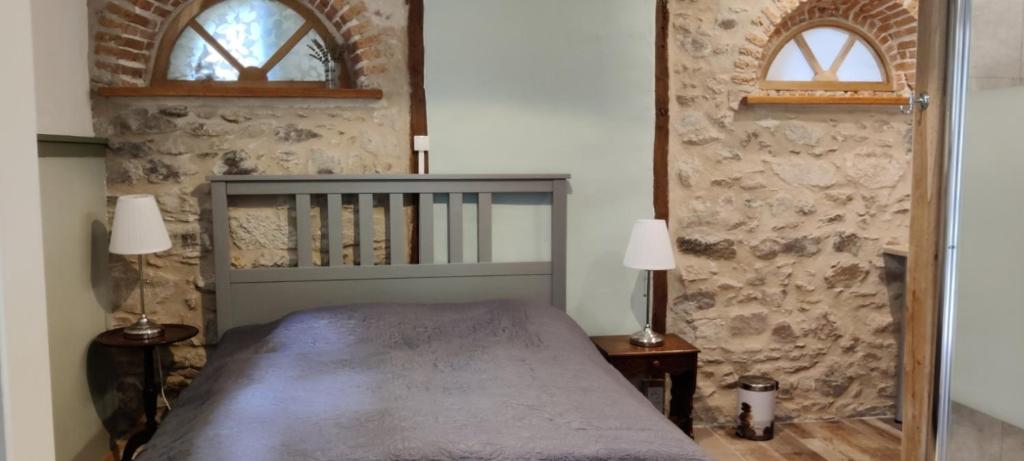a bedroom with a bed with two lamps and two windows at Gîtes du Castellare in Le Chalard