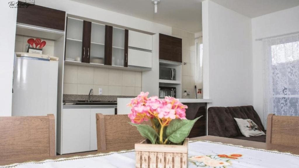 una cocina con una mesa con flores rosas. en Lindo Apartamento, amplo e confortável, Penha Santa Catarina,, en Penha