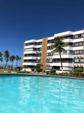 a large swimming pool in front of a building at Village pé na areia com limpeza in Lauro de Freitas