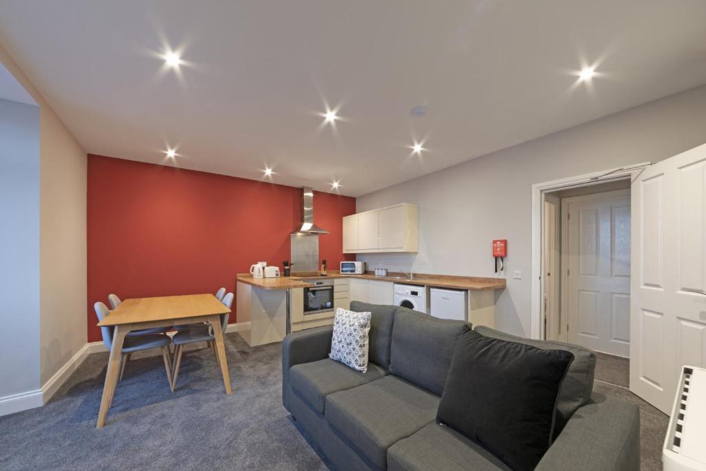 een woonkamer met een bank en een keuken bij K Suites - Waveney Chambers 1 in Lowestoft