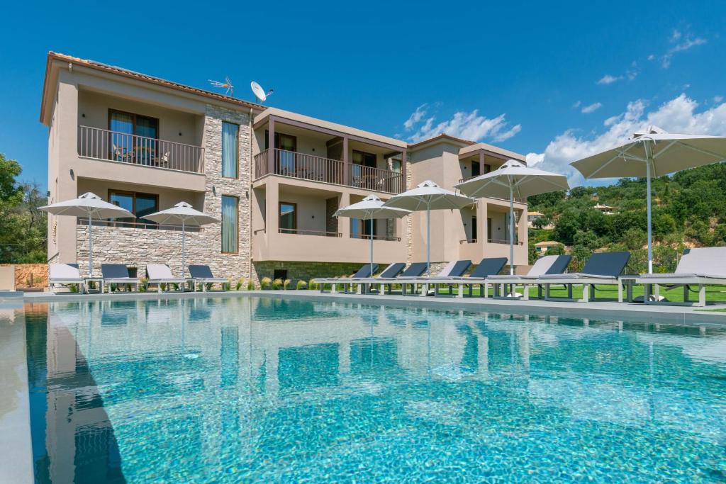 a swimming pool in front of a building with chairs and umbrellas at Neoma Luxury Residence - Adults Only in Sivota