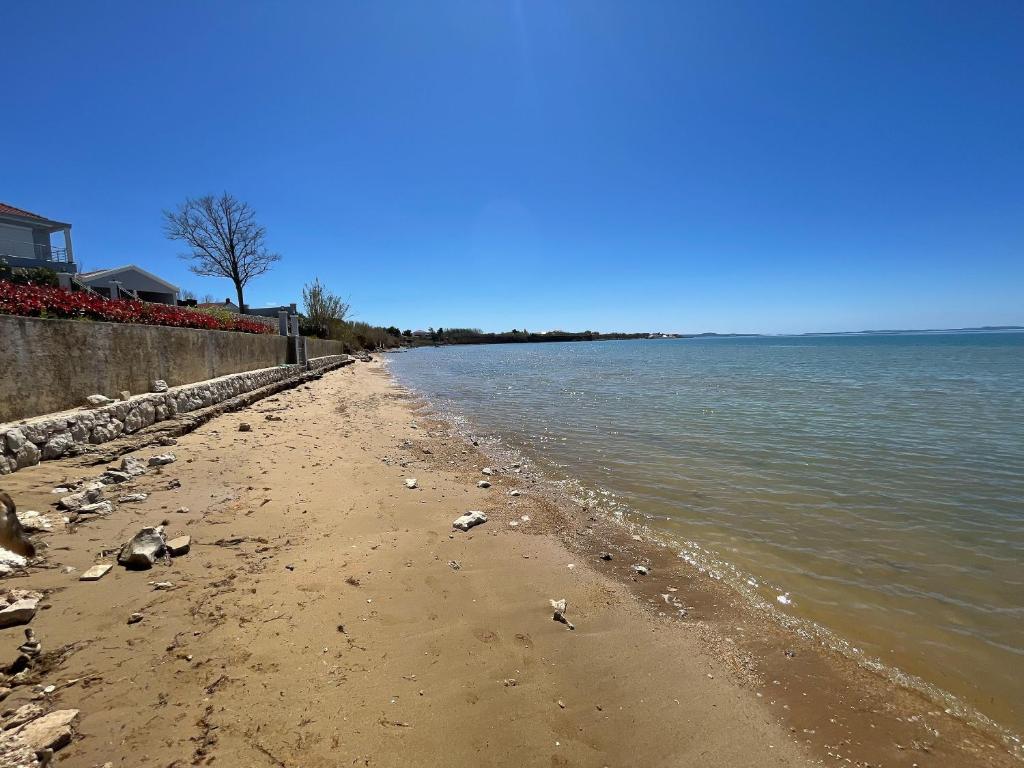 einen Strand mit Felsen und Wasser an einem klaren Tag in der Unterkunft Apartments AS in Privlaka