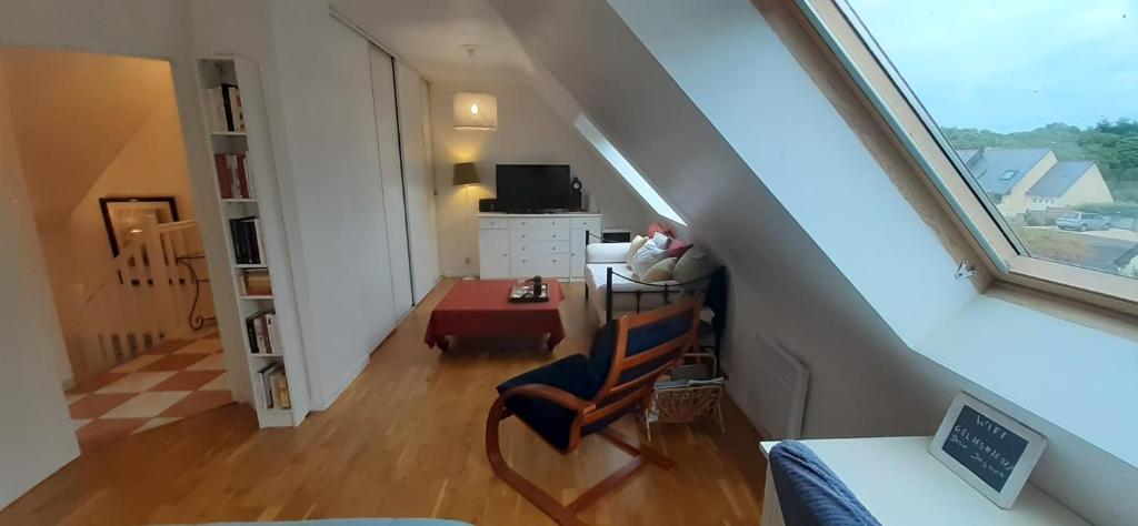 an attic room with a staircase with a chair and a desk at Tous à l'ouest in Combrit