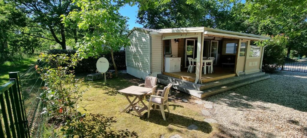 Mobile home avec terrasse et piscine. في هورتين: منزل صغير أخضر مع طاولة وكراسي