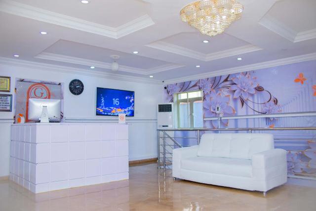 a living room with a white couch and a tv at Galpin Suites in Ikeja