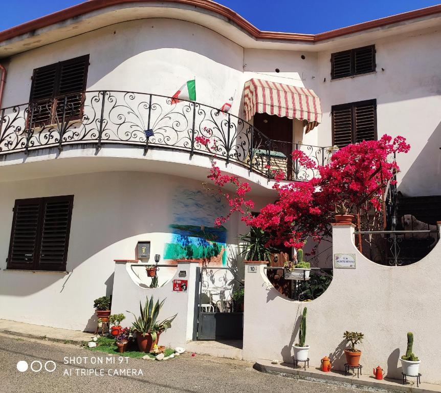 a white building with a balcony and flowers at Apartment Via Montenegro in Ghilarza