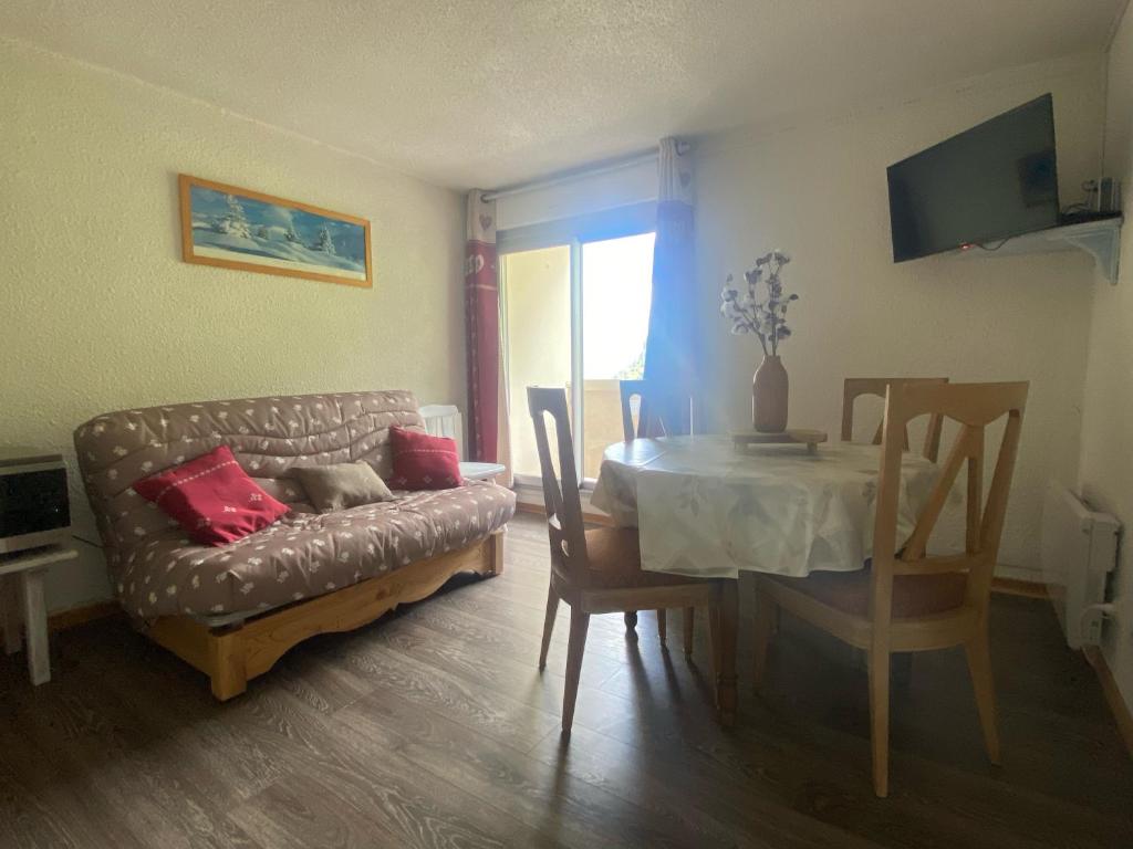 a living room with a couch and a table at Appt chaleureux 2 - 4 personnes au pied des pistes - draps et linges de toilette non fournis - ménage non inclus - attention rénovation de façade actuellement in La Mongie
