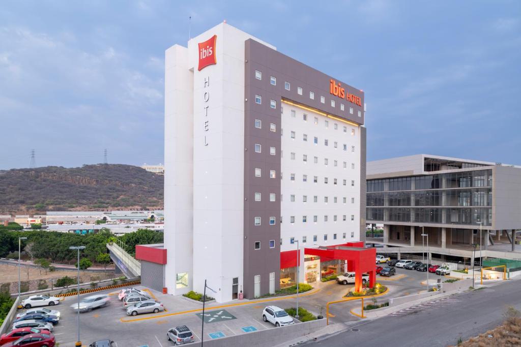 a white building with a red sign on top of it at Ibis Queretaro in Querétaro