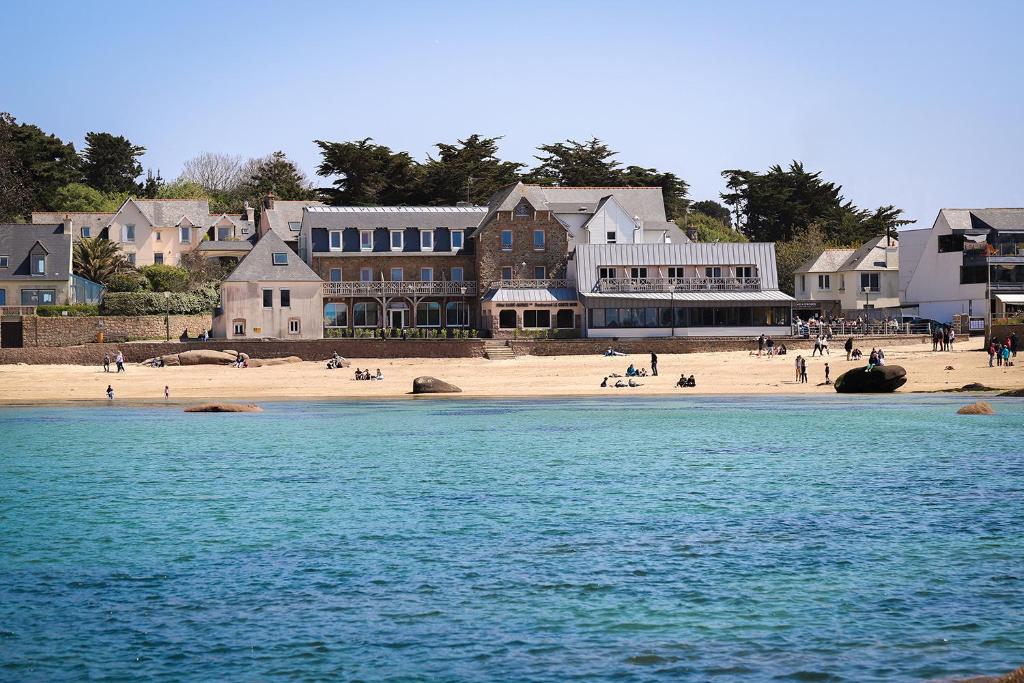 a beach with people on the sand and buildings at Logis Hôtel Saint Guirec Et De La Plage in Perros-Guirec