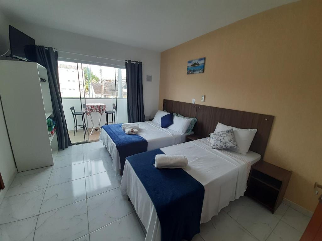 a hotel room with two beds and a balcony at Pousada APART PenhaFlat- Studio a 700 mts do parque in Penha