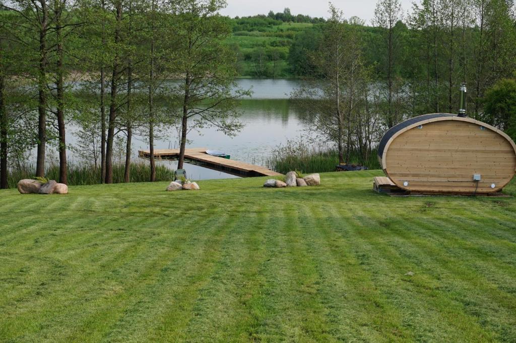 ein kleines Holzboot auf einem Grasfeld neben einem See in der Unterkunft R&M Resort in Petkėniškės