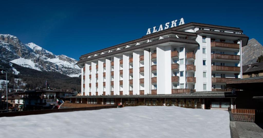un grand bâtiment avec de la neige devant lui dans l'établissement Hotel Alaska Cortina, à Cortina dʼAmpezzo