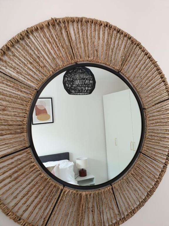 a round mirror with a rattan wall at Cheerful 1 private room-ensuite with free parking in Silverdale