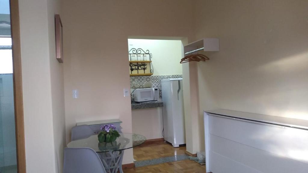 a kitchen with a glass table and a refrigerator at Flat em local tranquilo, com garagem compartilhada a dois quarteirões do centro histórico, 15 min de Tiradentes in São João del Rei