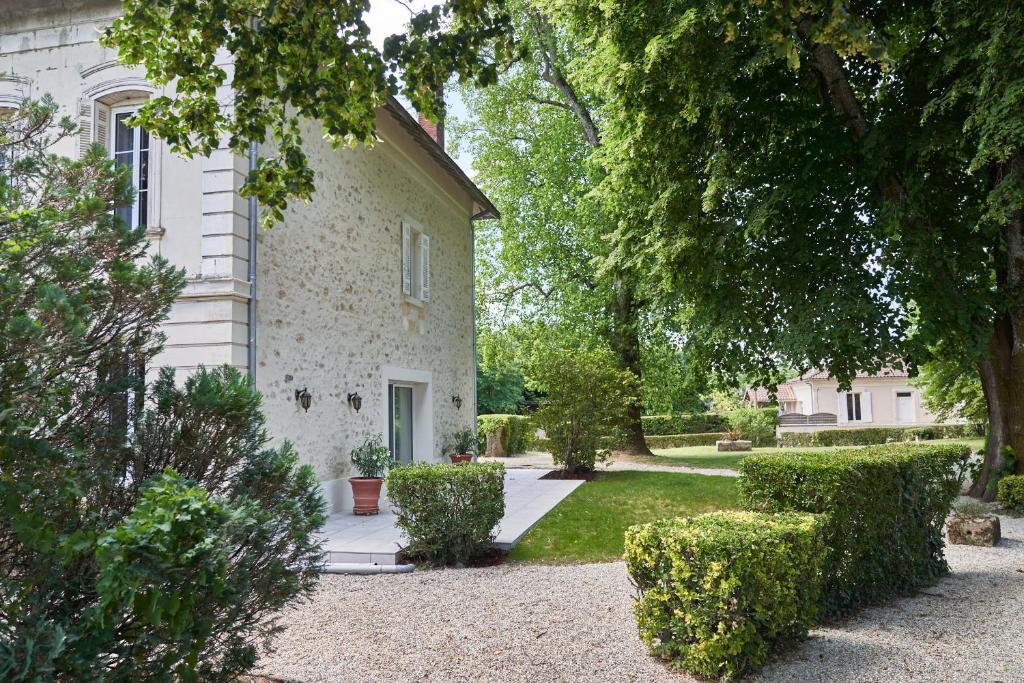 uma grande casa branca com árvores e arbustos em CHATEAU BELAIR-Séjour Prestige em Sainte-Croix-du-Mont