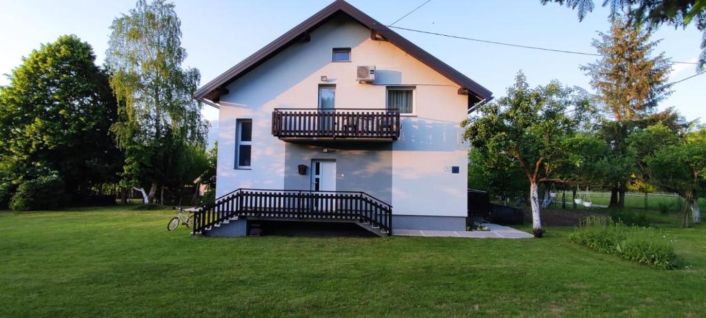 a house with a balcony and a yard at Apartment Gradina in Korenica