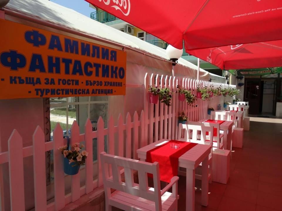 a pink restaurant with white tables and a red umbrella at Familia Fantastiko - Family Hotel in Kiten
