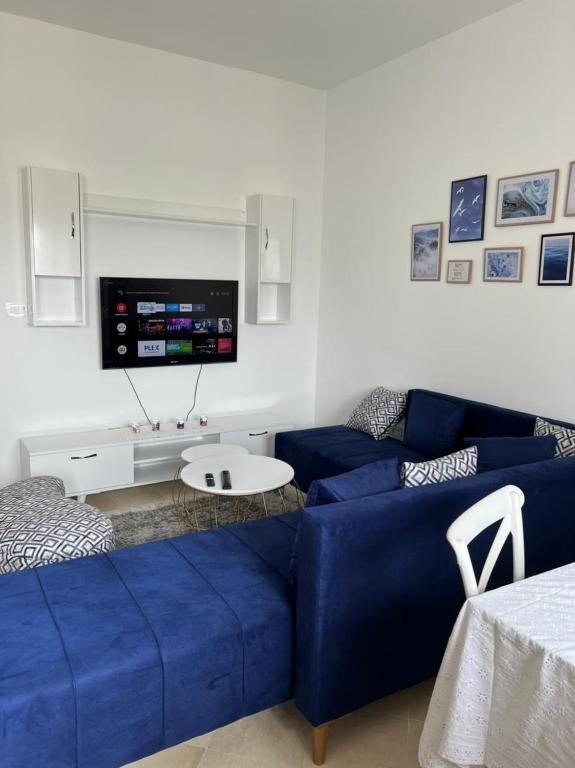 a living room with a blue couch and a tv at Residence Mariem in Ariana