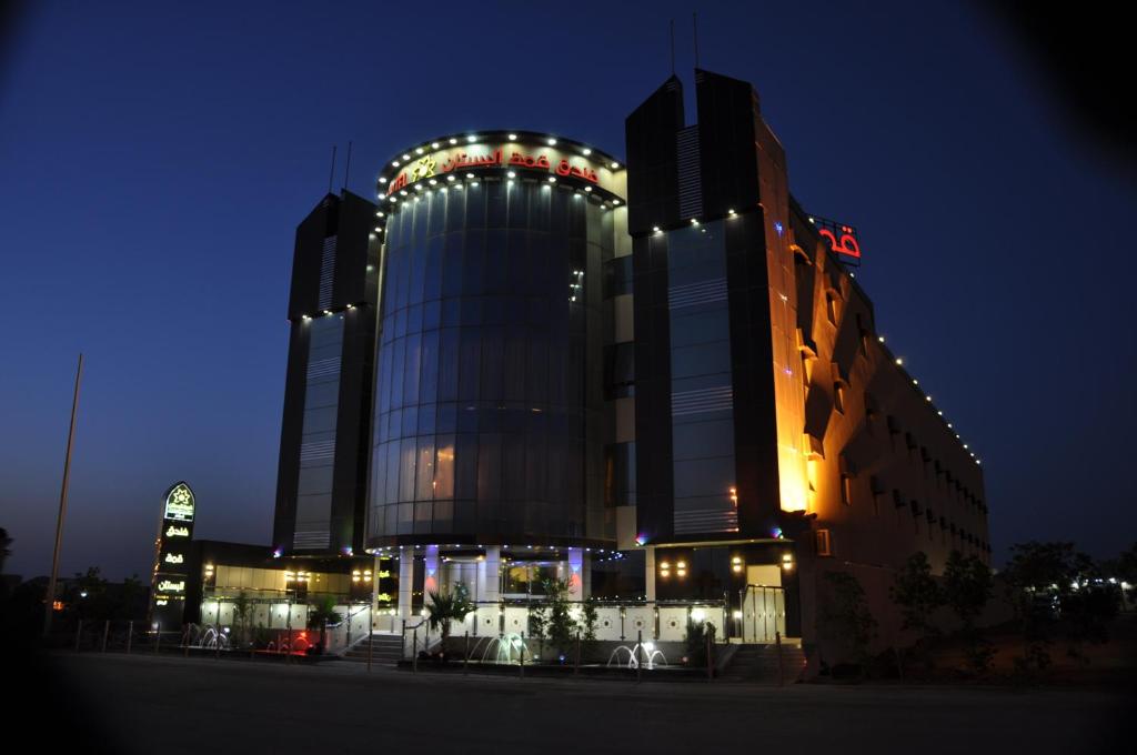 a large building with lights on it at night at Al Bustan Crown Hotel 2 in Arar