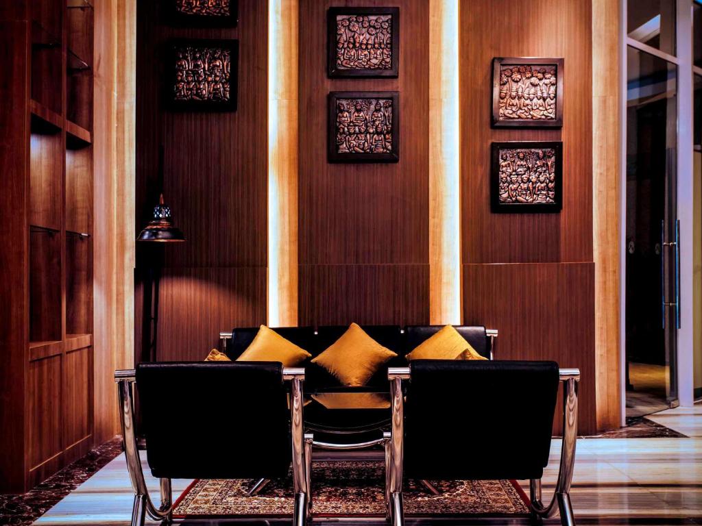 Grand Mercure Yogyakarta Adi Sucipto في يوغياكارتا: غرفة طعام مع طاولة مع وسائد صفراء