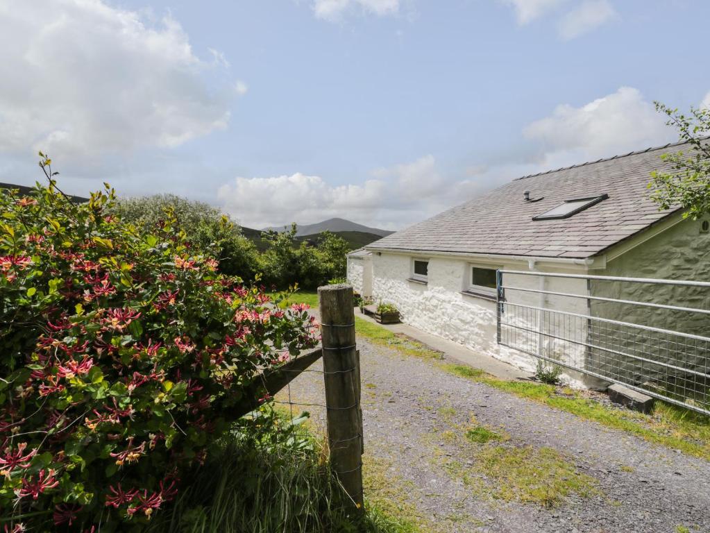 a house with a fence and flowers in front of it at Y Bwthyn in Dinorwic