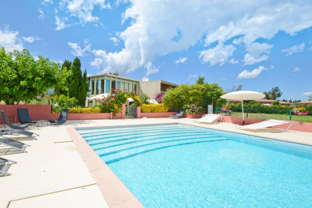 una piscina con sillas y sombrilla en Hôtel Les Jardins en Lucciana