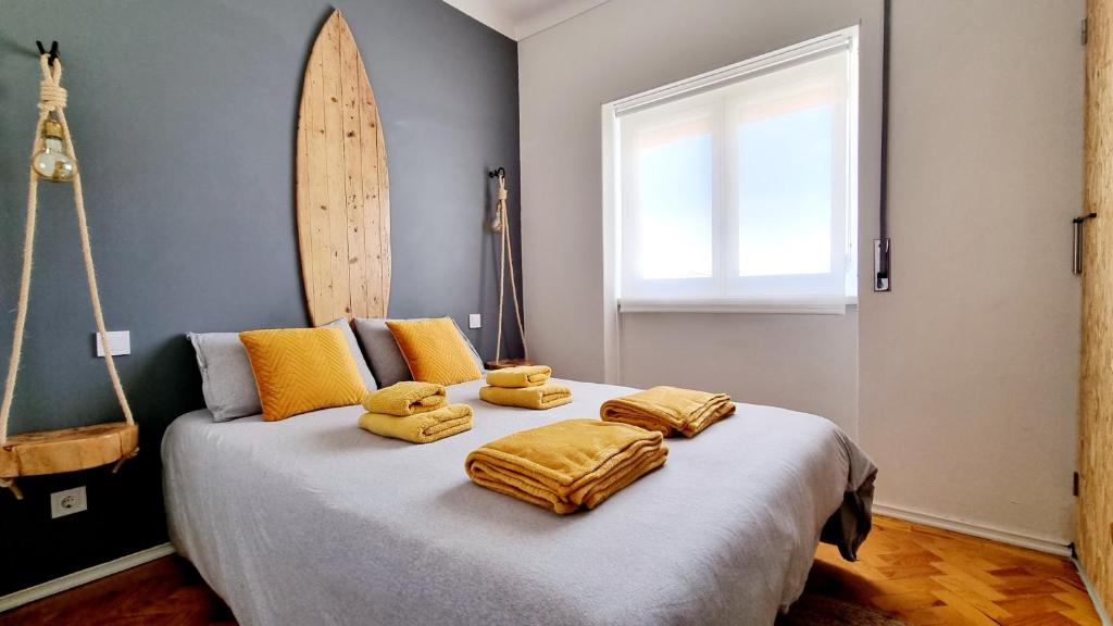 a bedroom with a bed with yellow pillows and a surfboard at Family Surf Home - Hostel in Mafra