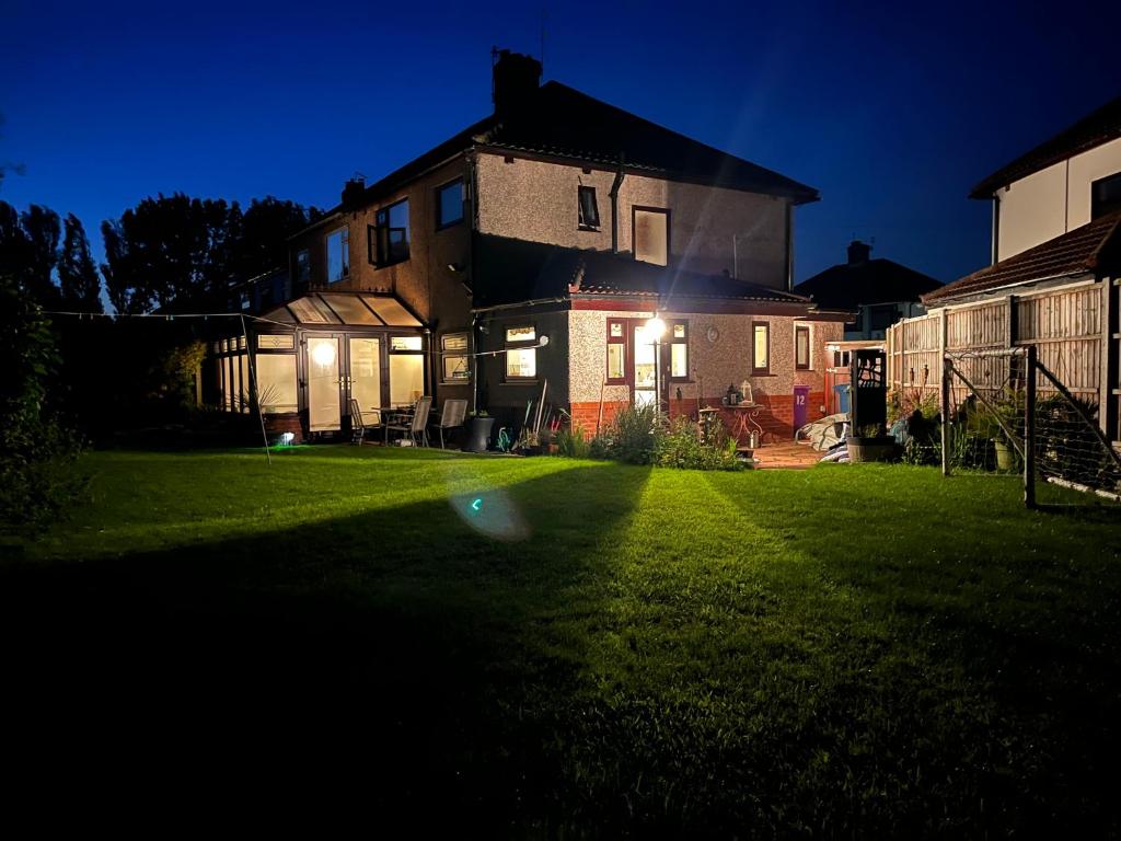 a house with lights on a yard at night at Greenacre House close to Liverpool John Lennon Airport in Woolton