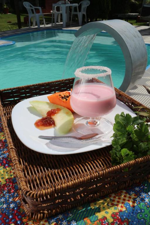 a plate of fruit and a drink on a table near a swimming pool at Pousada da Teteia in Praia Sêca