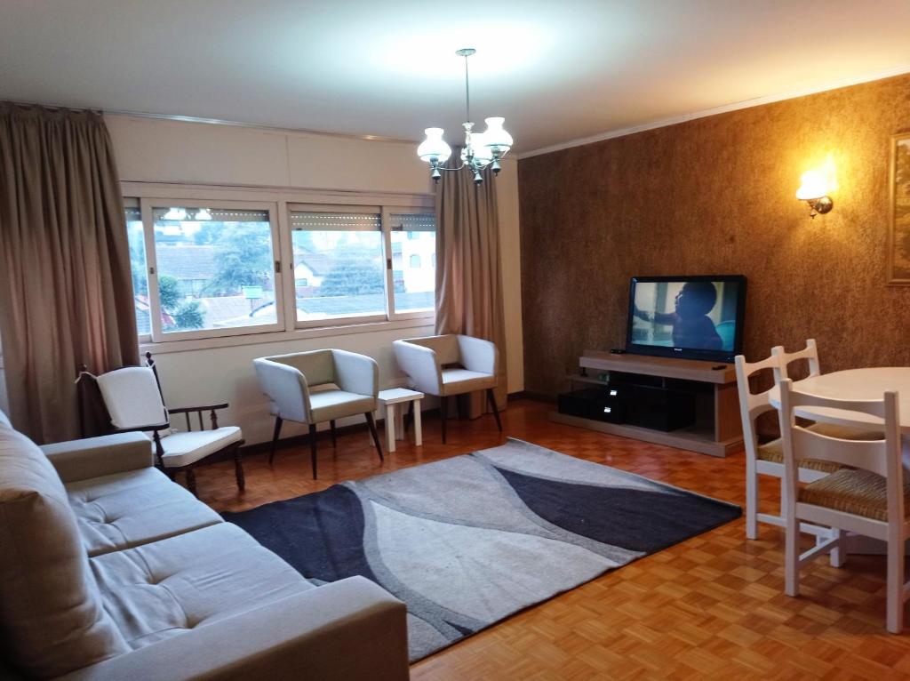 sala de estar con sofá, sillas y TV en Amplo e Central Apartamento 3 Quartos, en Gramado