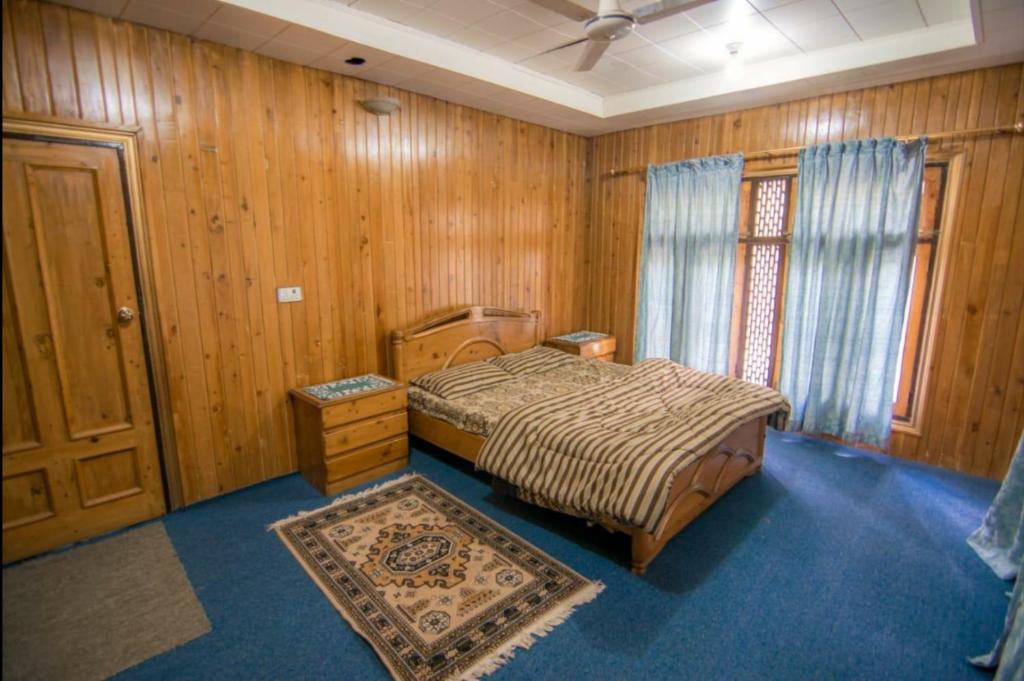 1 dormitorio con cama, paredes de madera y ventana en Al Amin Guest House - Home away from Home, en Skardu